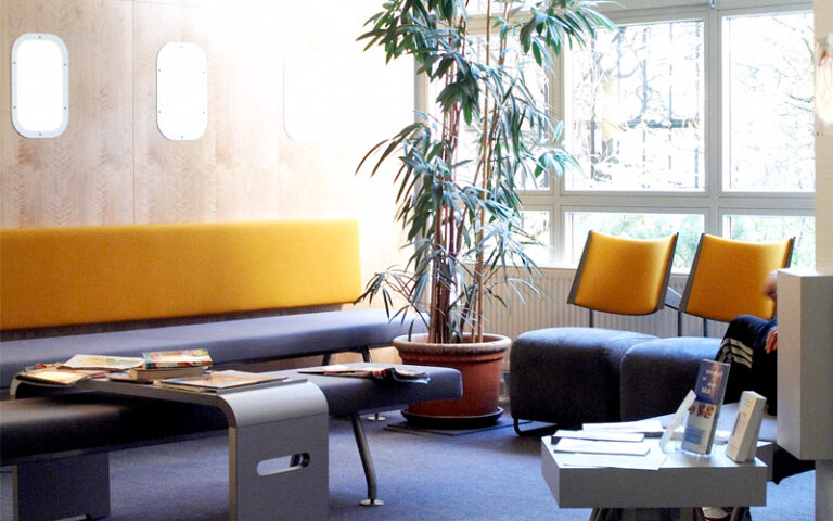 Modernes Wartezimmer mit bequemen Sitzmöbeln, heller Atmosphäre und Zeitschriften.